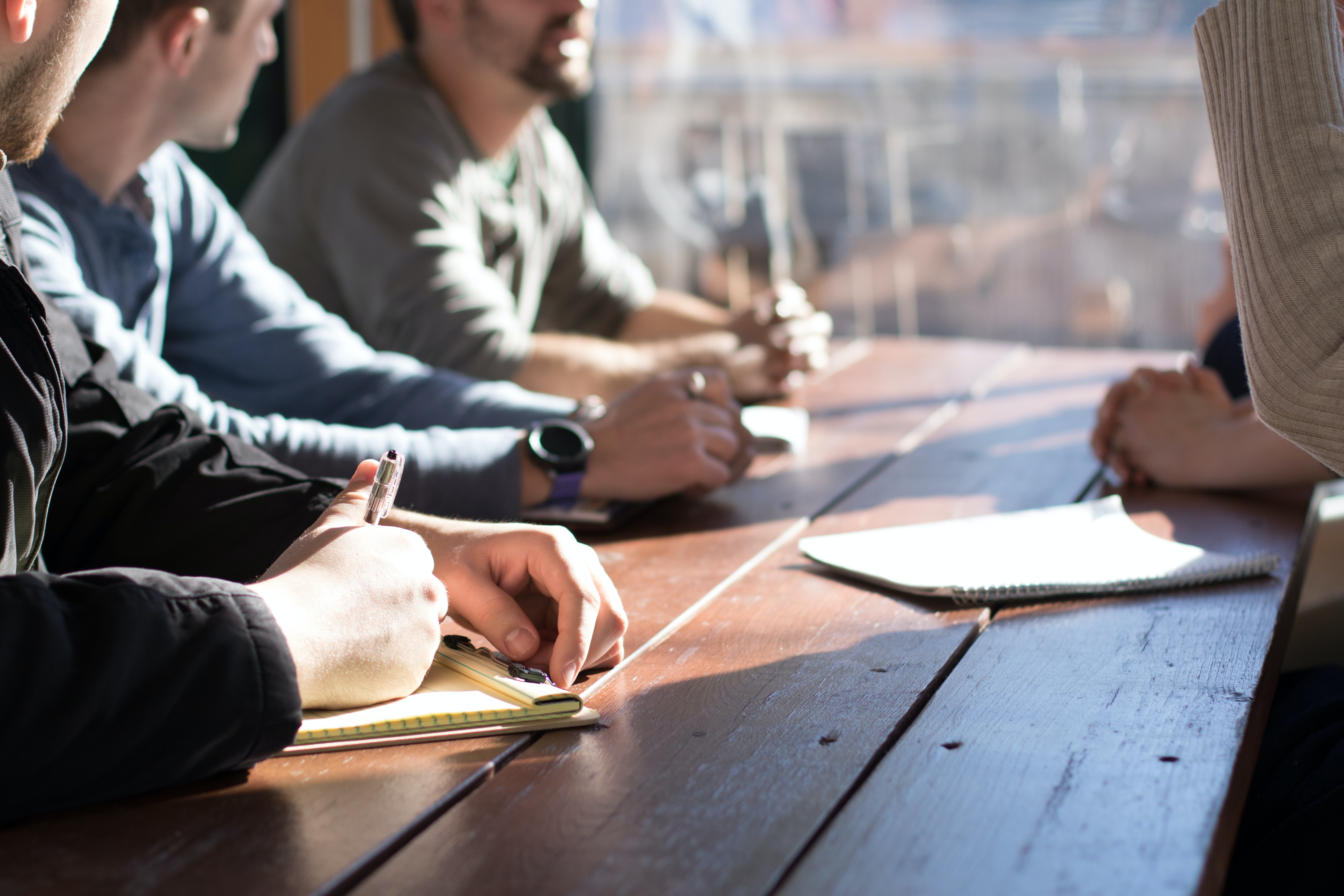 People discussing something with notebooks on a wooden table