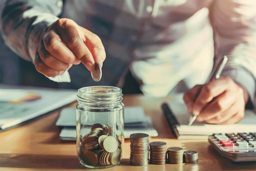 Person holding a pen and taking notes of coins being put on a jar