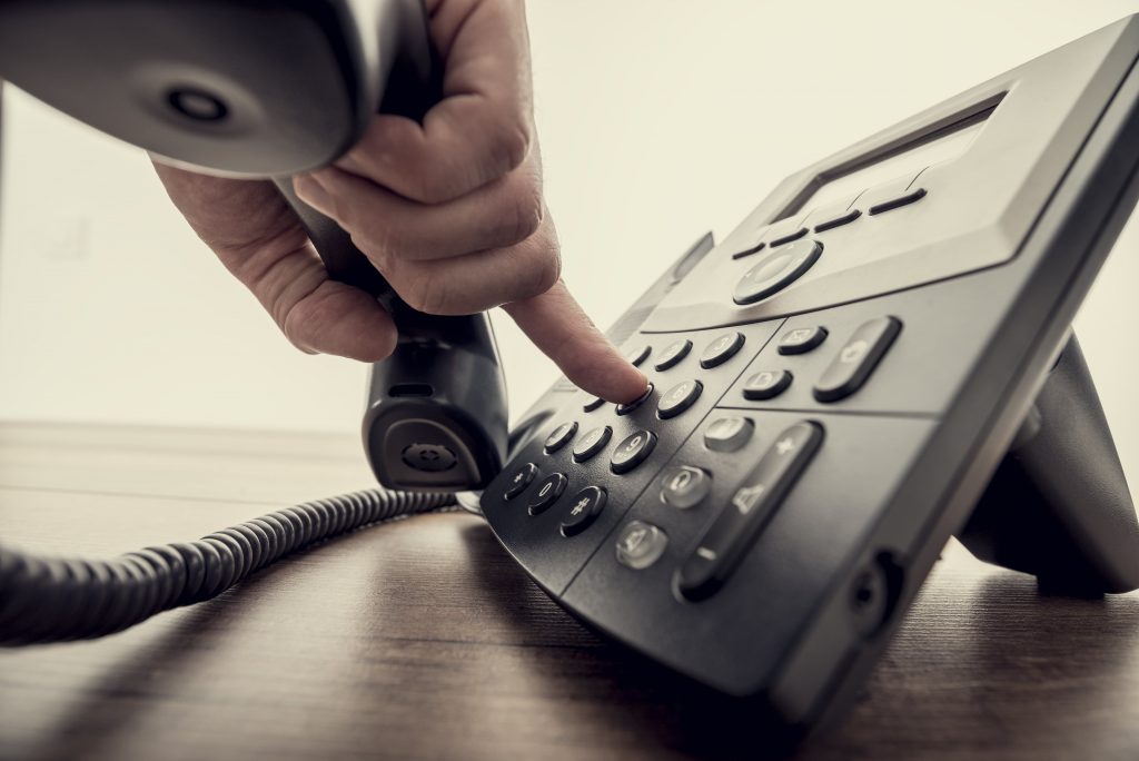 A hand dialing on a telephone