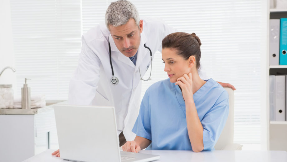 A doctor with a lady seated both looking at the laptop