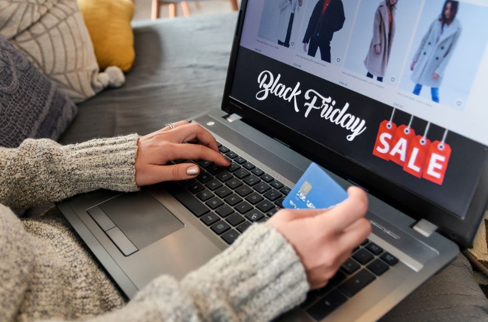 A hand using a laptop and holding a card