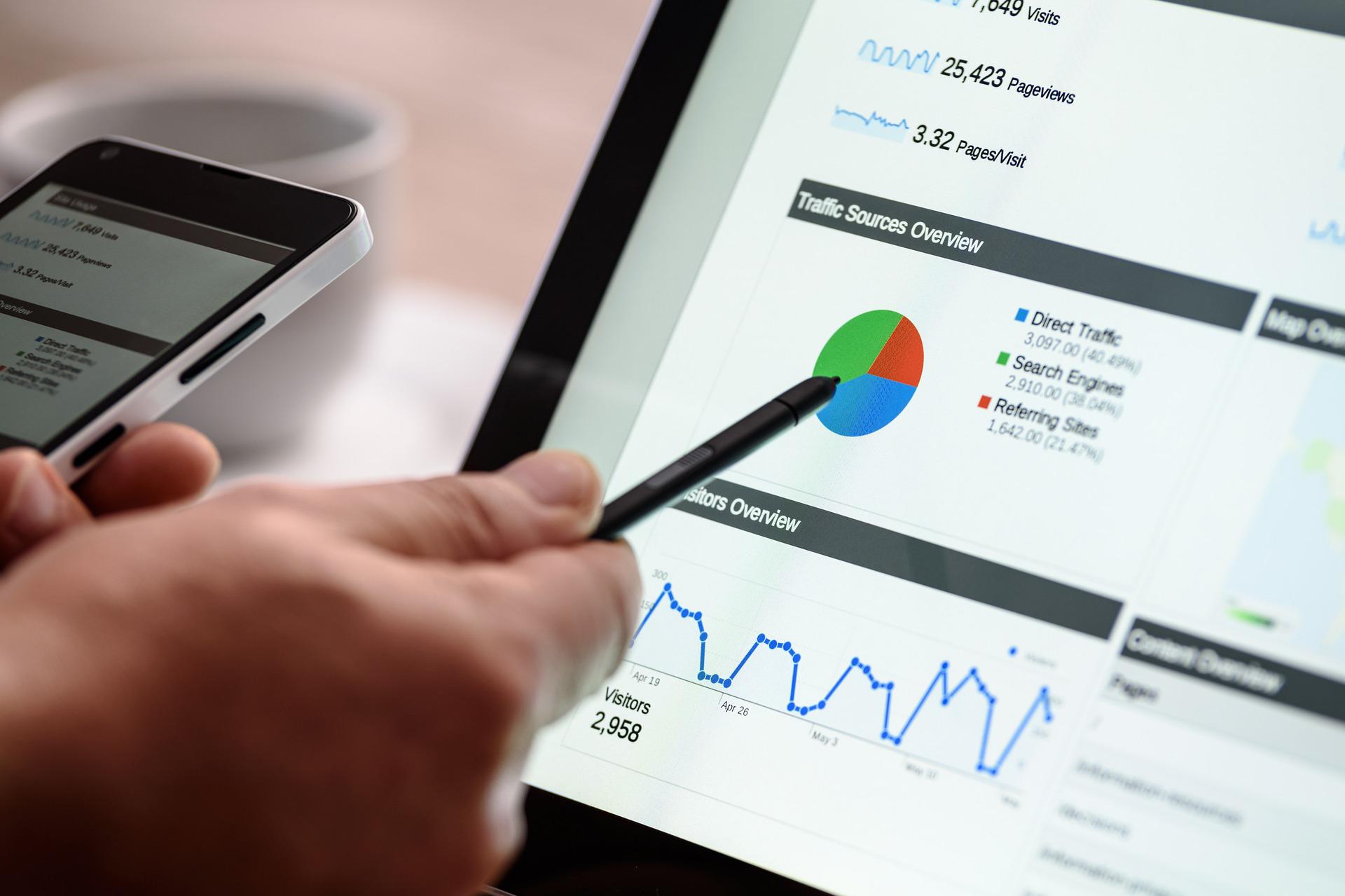 A hand holding a pen and pointing at the traffic graph on the screen