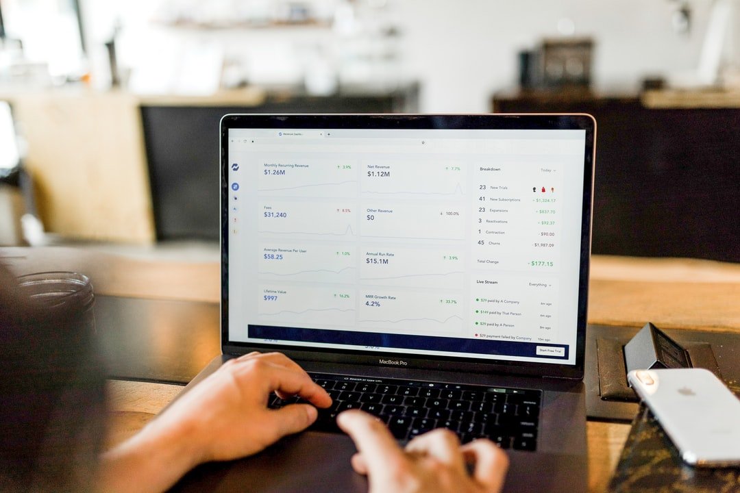 Hands typing in a laptop with revenue reports