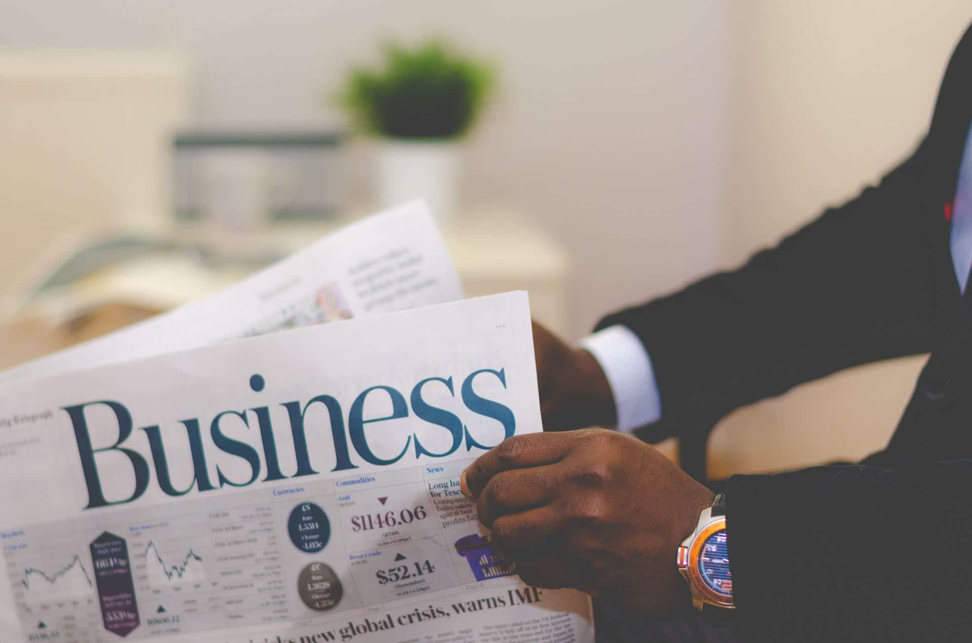 A man in black suit holding a business newspaper