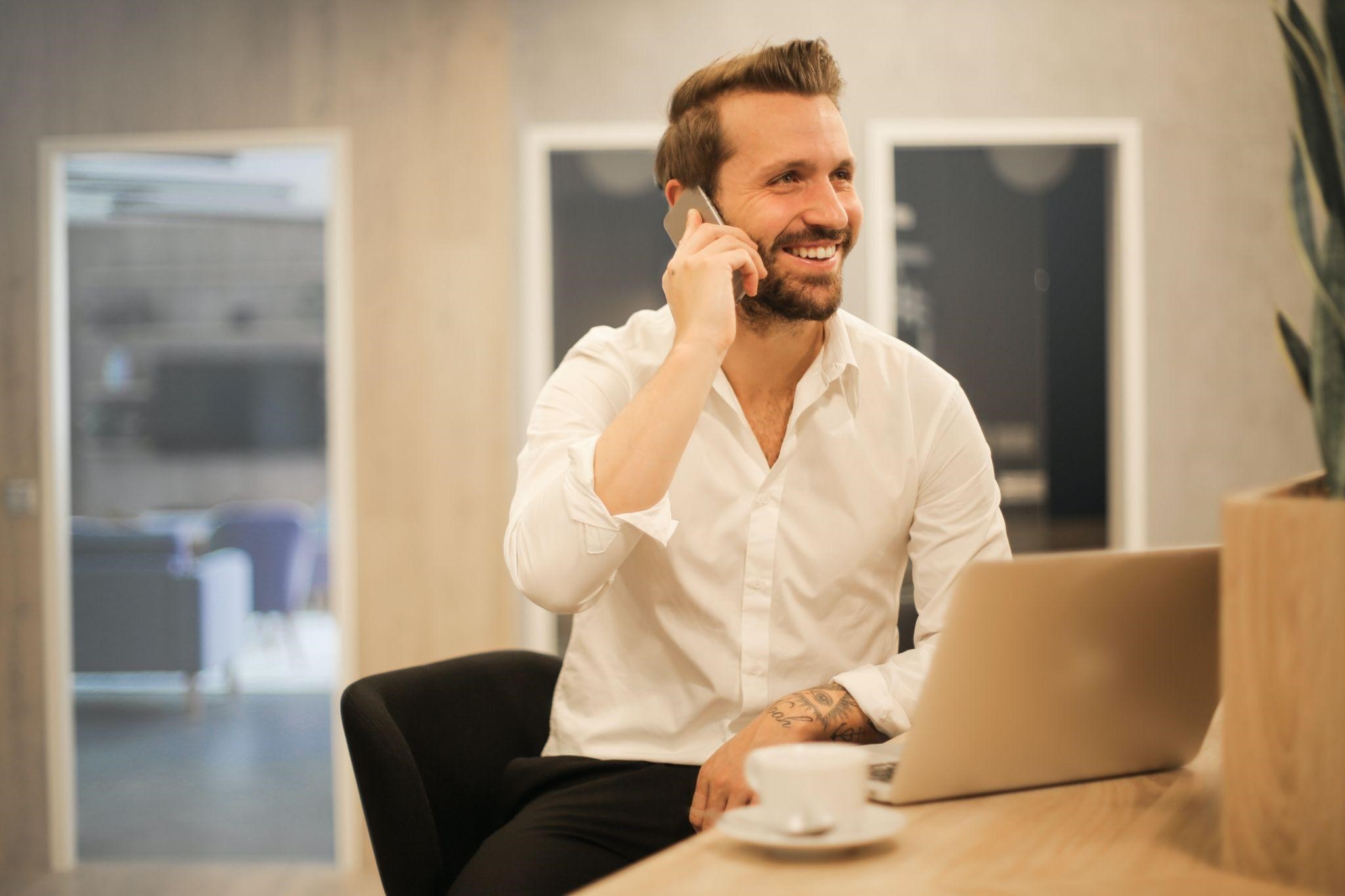 A man talking on phone with a laptop in front of him