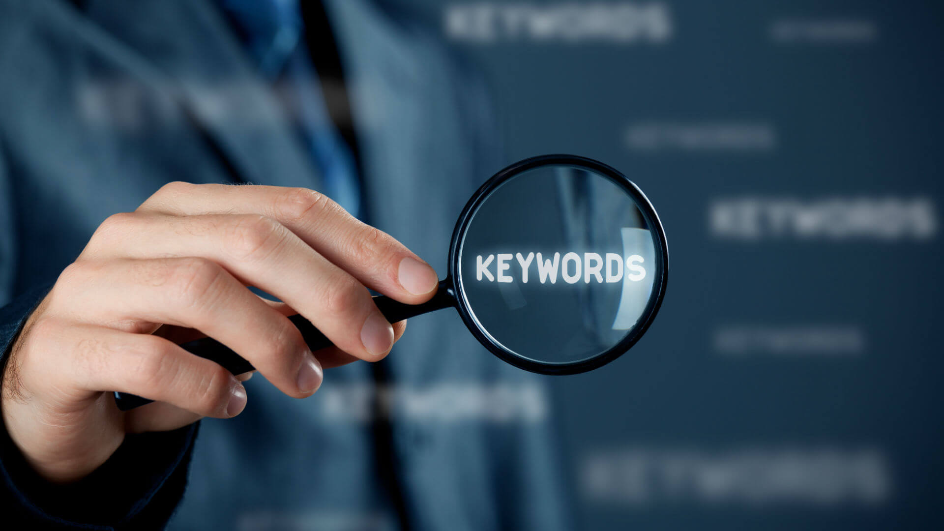 A man with a magnifying glass focusing on the word "Keywords"