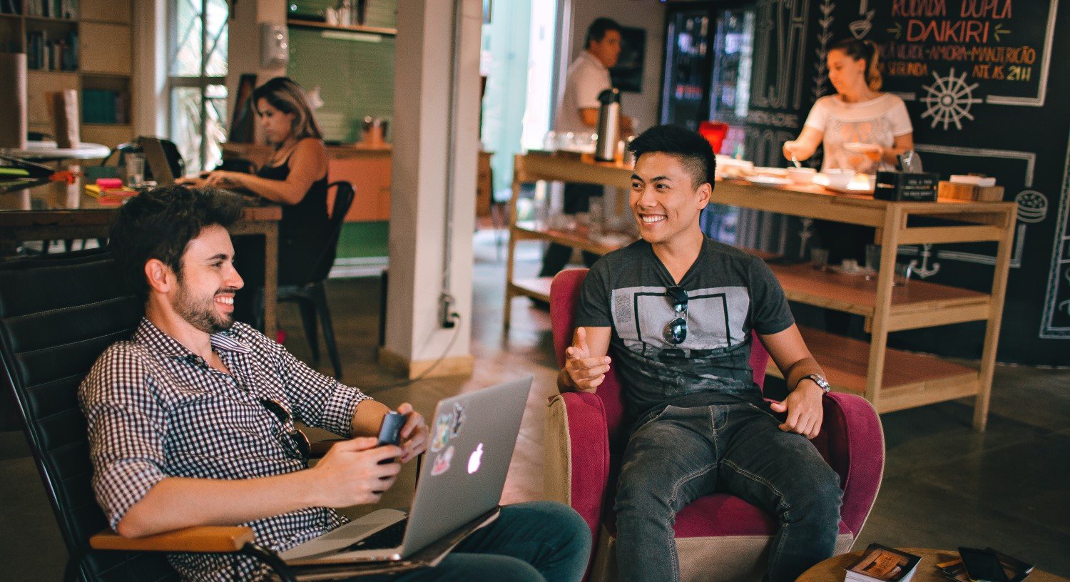 Two man talking and a laptop on a man's lap