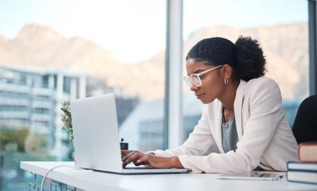 A woman in white coat typing in a laptop