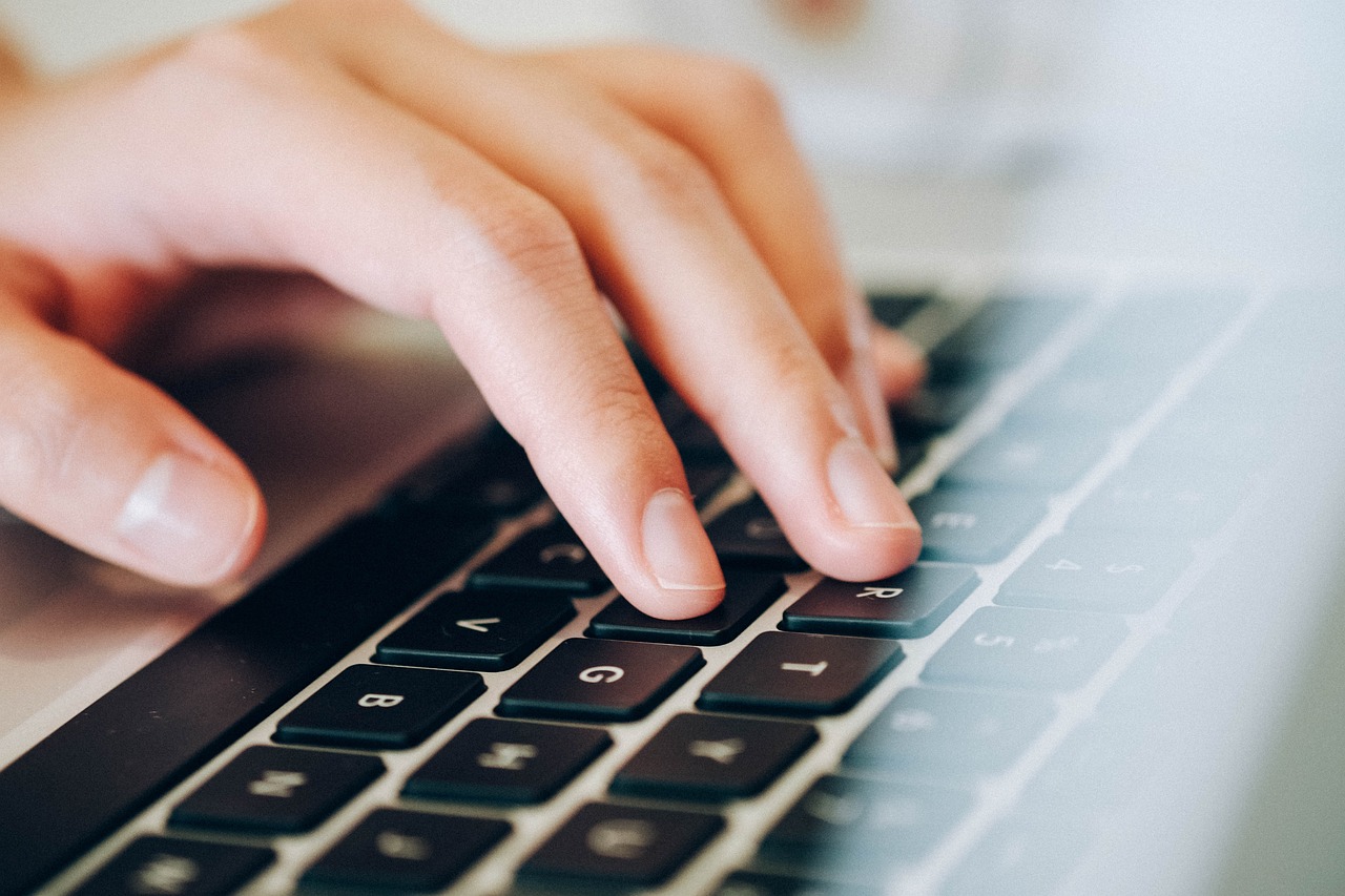 Hand typing on laptop keyboard