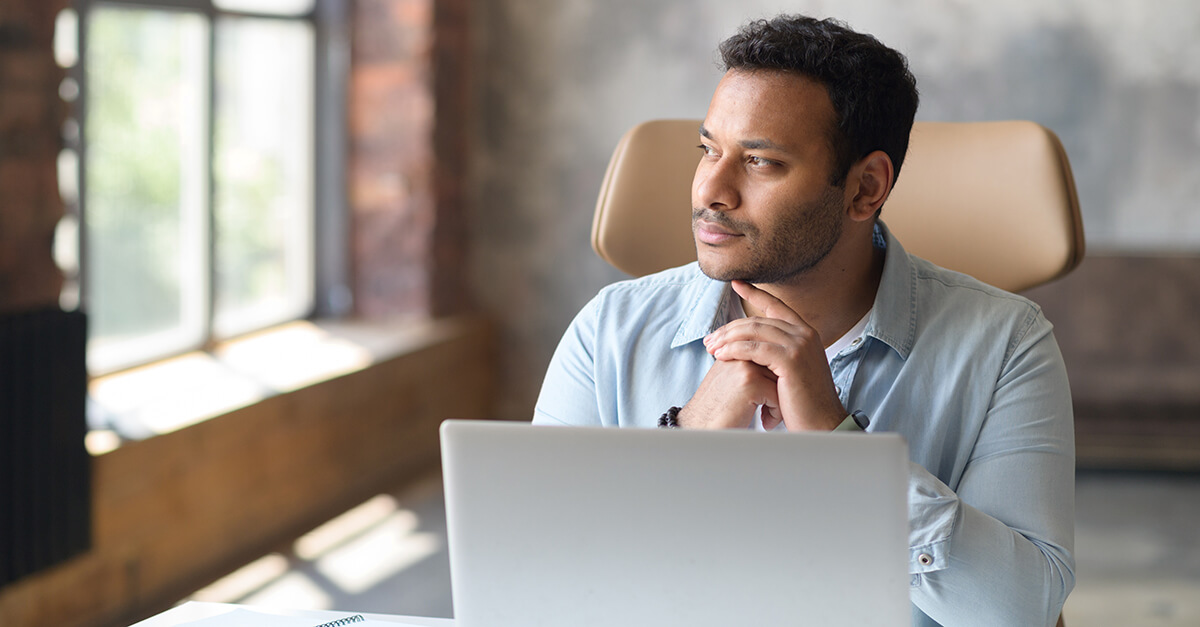 A man in light blue polo long sleeves in front of a laptop