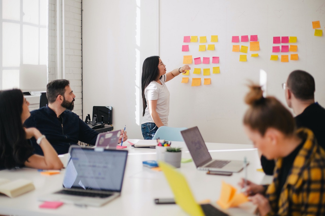 A female business head discusses with her team the notes on colored Post Its about storytelling in marketing