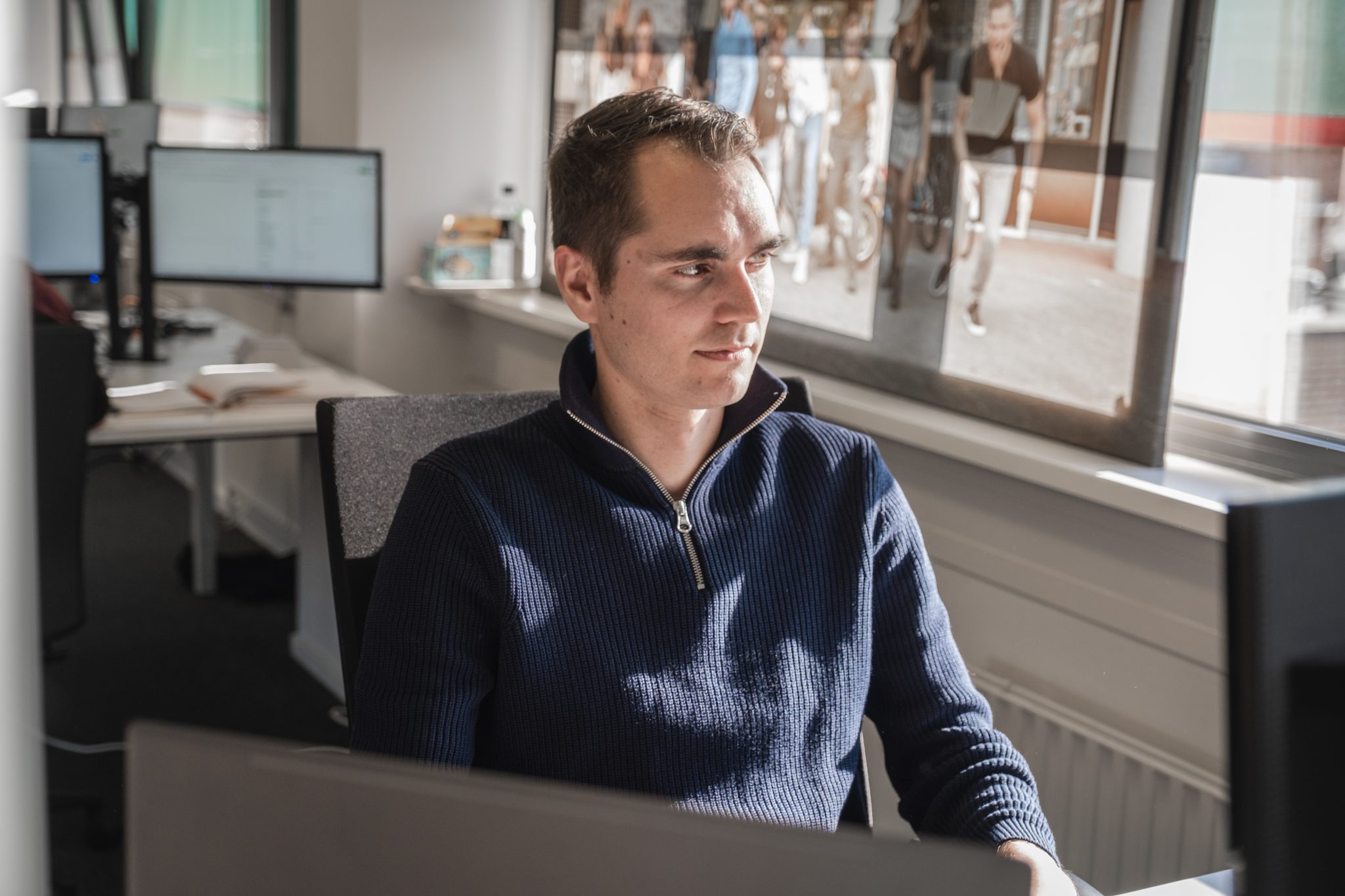 A maan in blue jacket in front of a computer