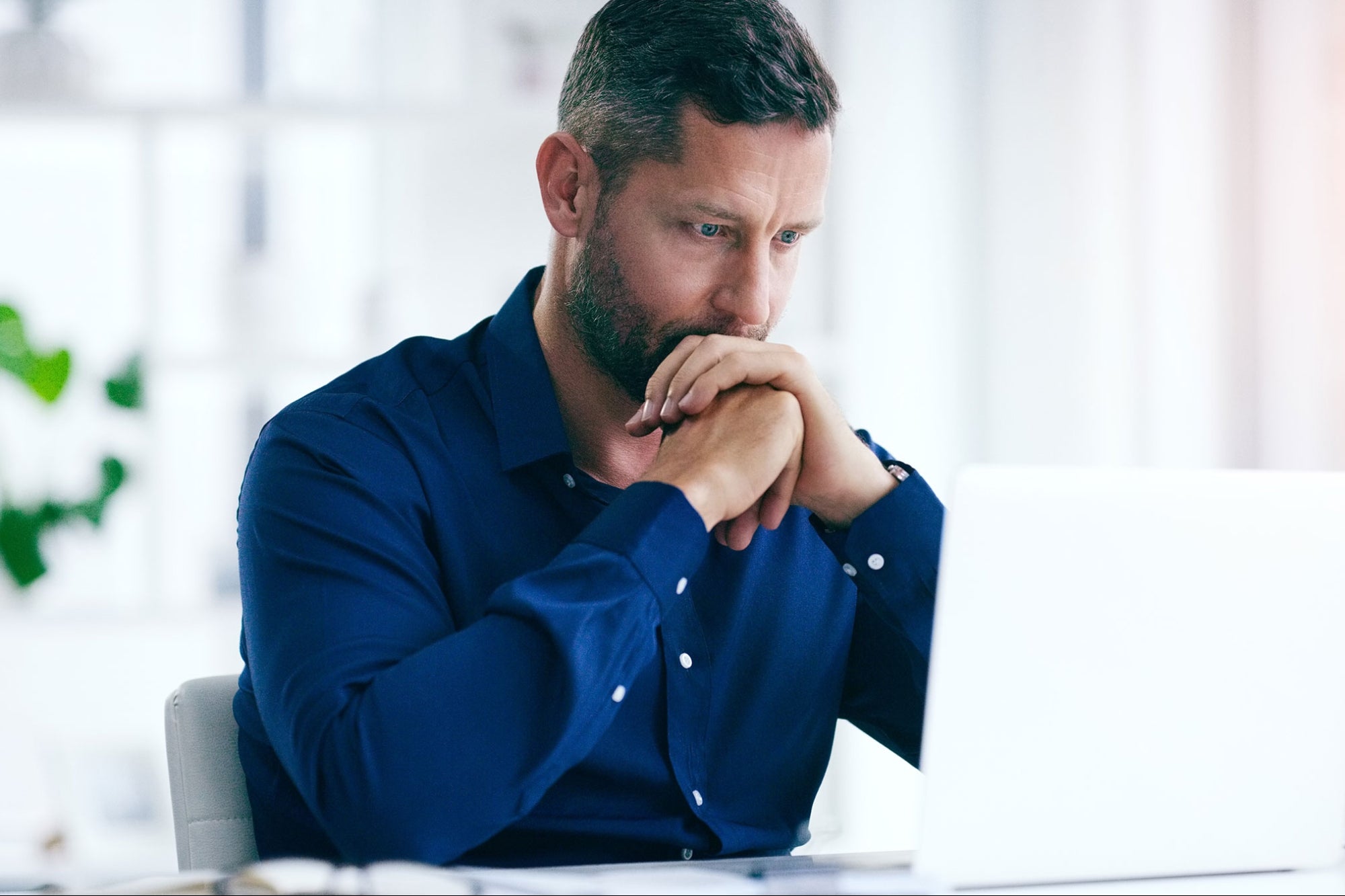 A man in blue polo long sleeves in front of a laptop