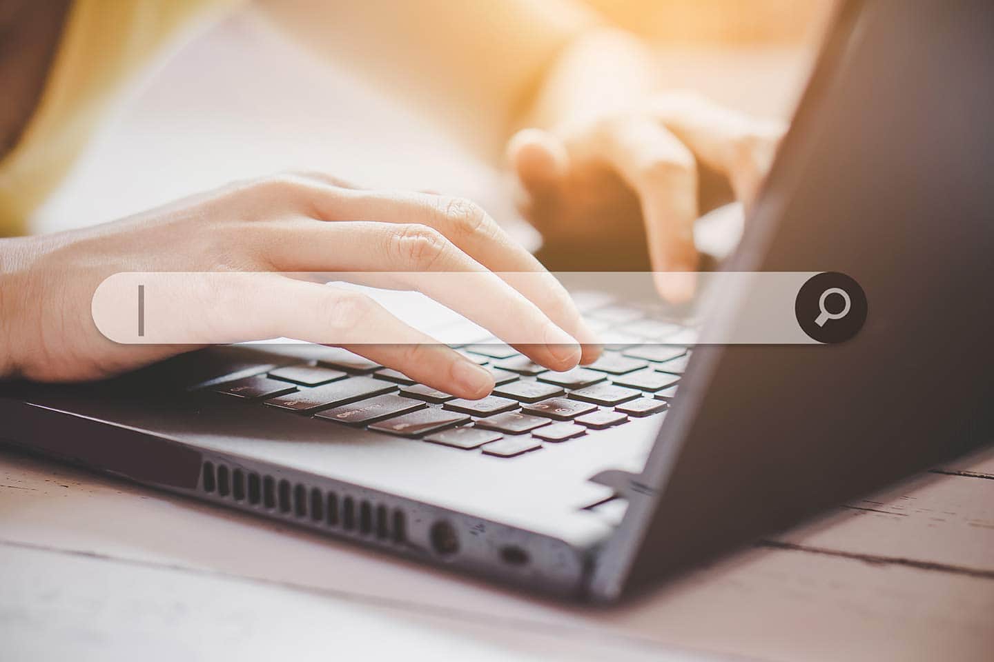 Hands typing on a keyboard laptop with search bar
