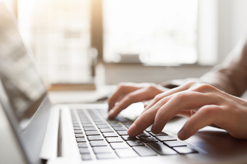 Hands typing on a keyboard laptop