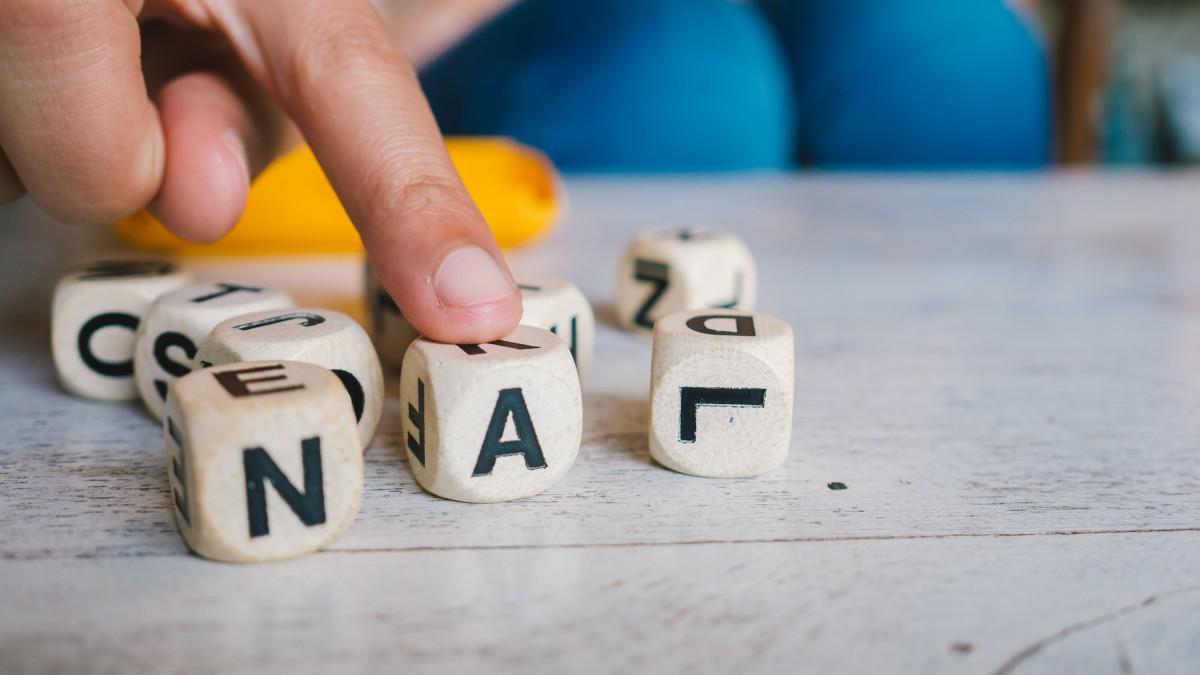 Finger touching wooden letter blocks