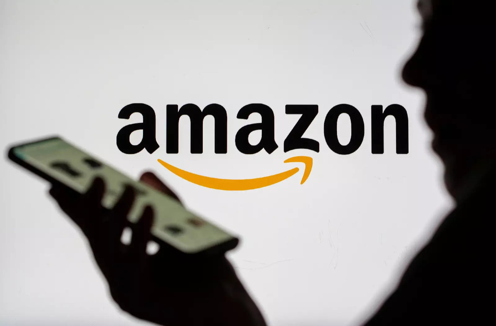 Amazon logo and a person holding a phone