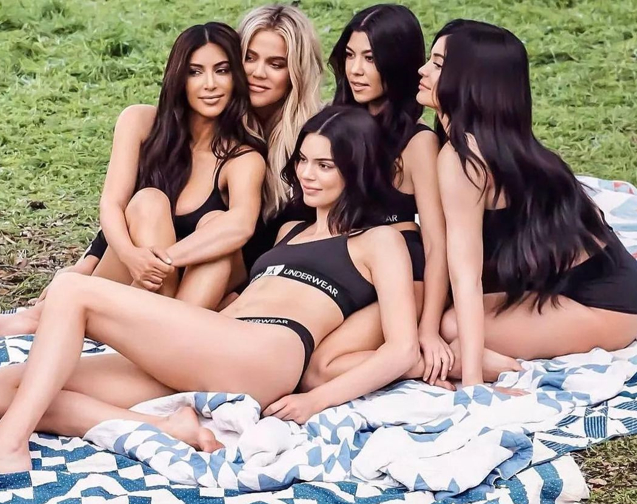 Kim, Khloe and Kourtney Kardashian and Kylie and Kendall Jenner seated on the ground posing together