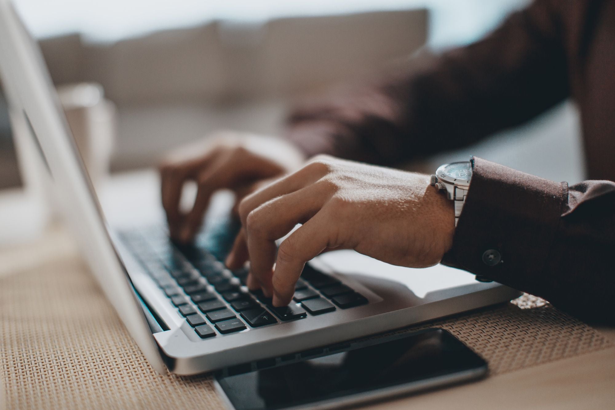 A man wearing a coat typing on a laptop