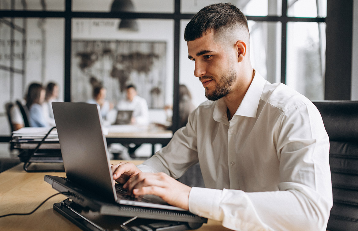 A man in white polo long sleeves typing on a laptop