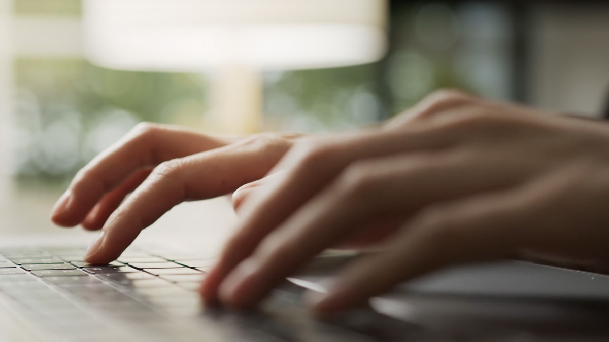 Hands typing on a laptop keyboard