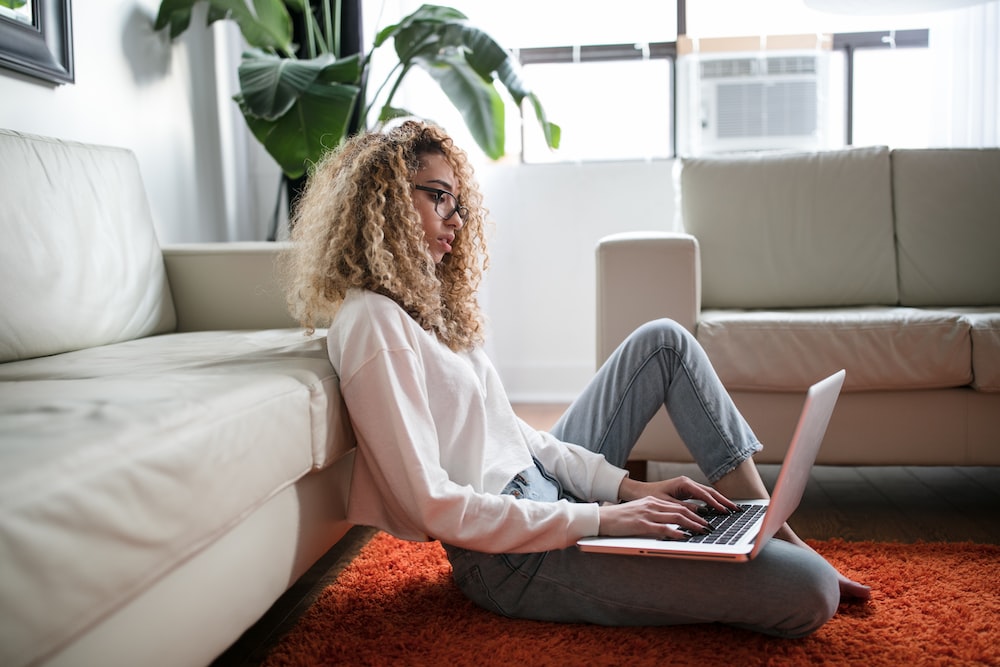A woman in whte long sleeves with a laptop on her lap