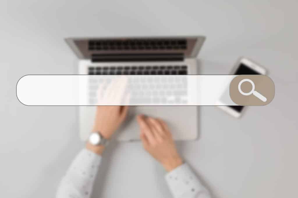 Hands typing on a laptop and a search bar
