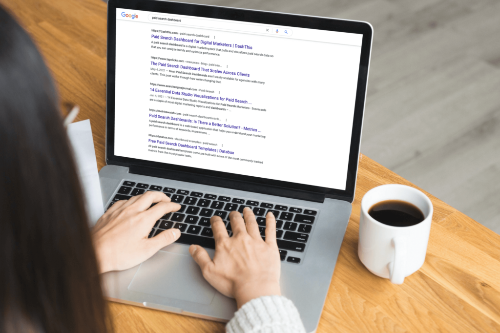 A woman typing on a laptop with cup of coffee on the side