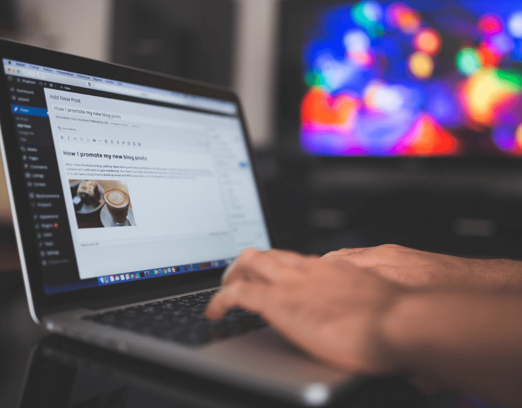 Hands typing on a laptop with cofee on the monitor
