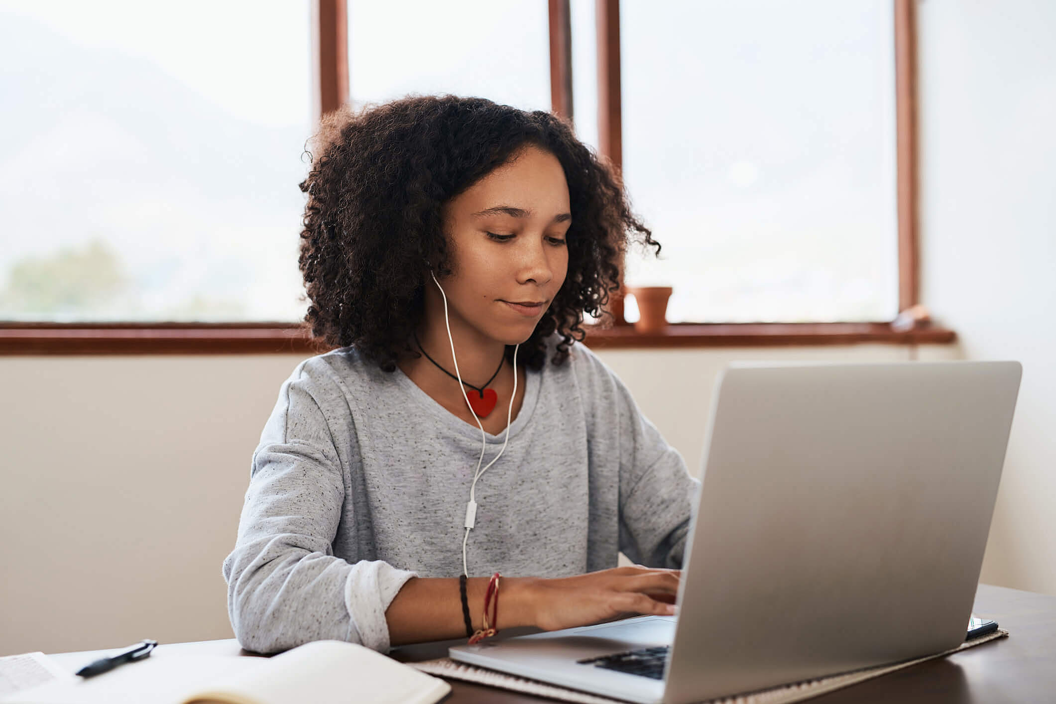 A woman in gray sweater typing on a laptop