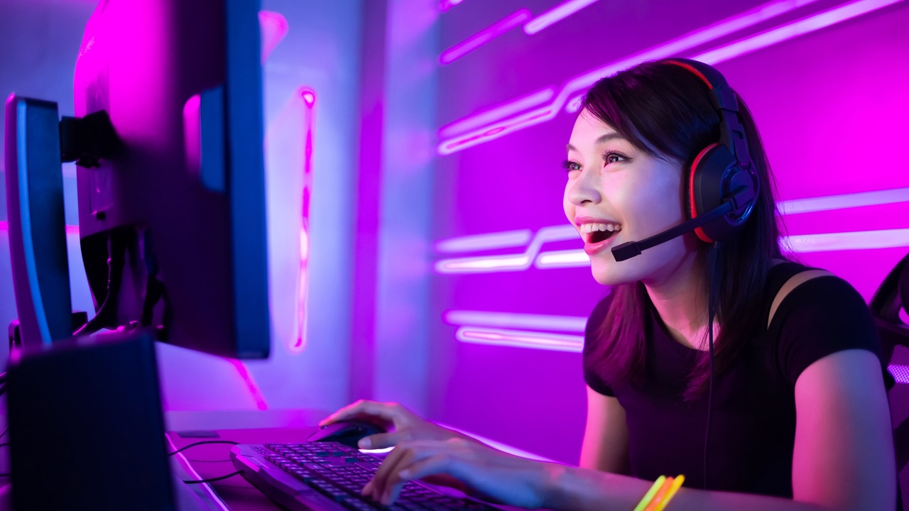 A woman with black headphones typing on a computer keyboard