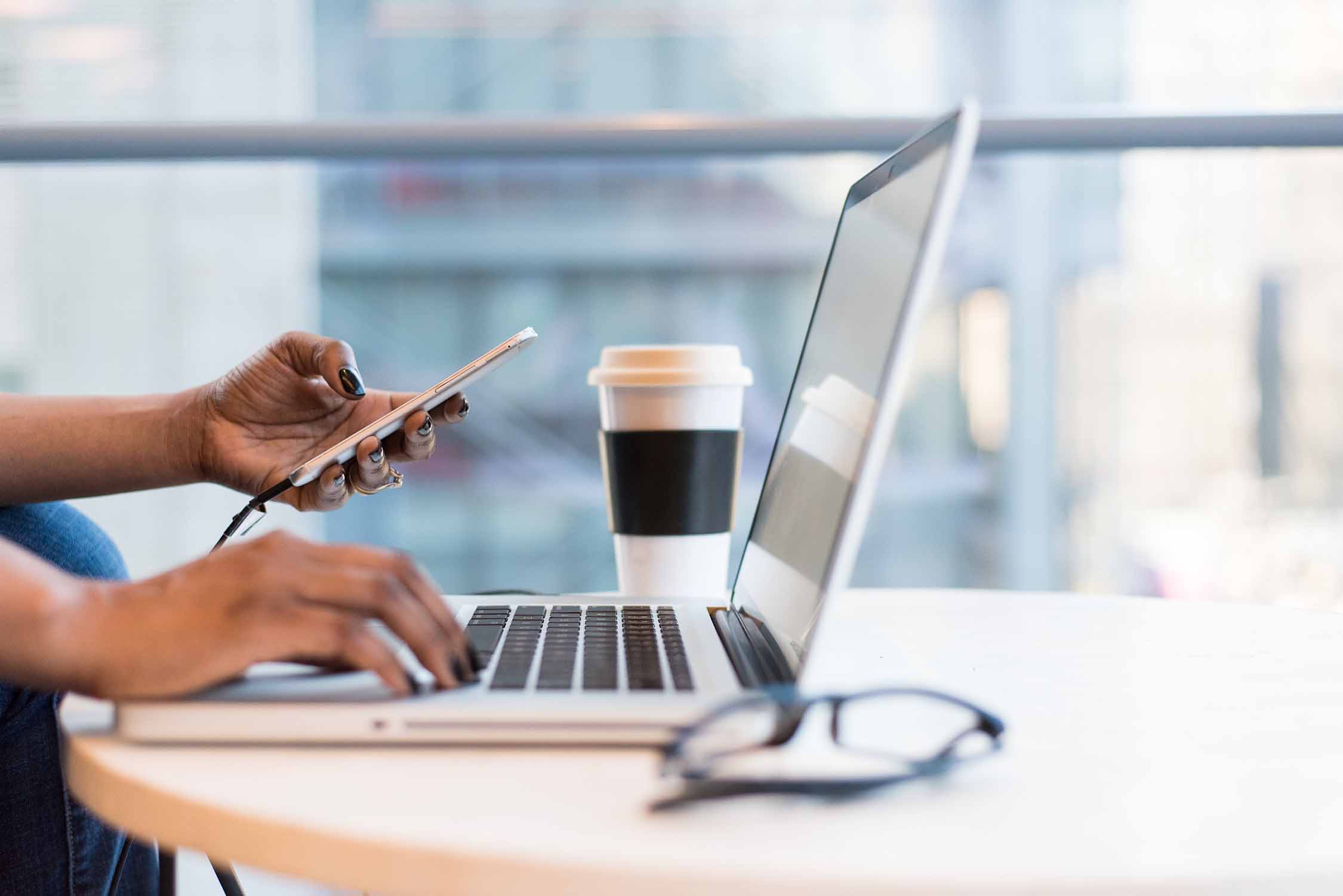 Hands holding a phone and laptop keyboard
