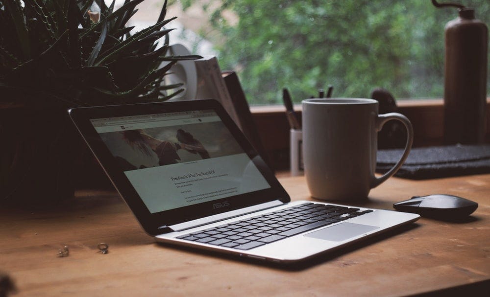 Laptop and white mug beside it