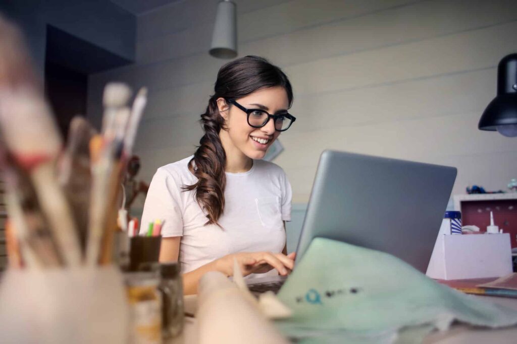 A woman in white shirt in front of a gray laptop