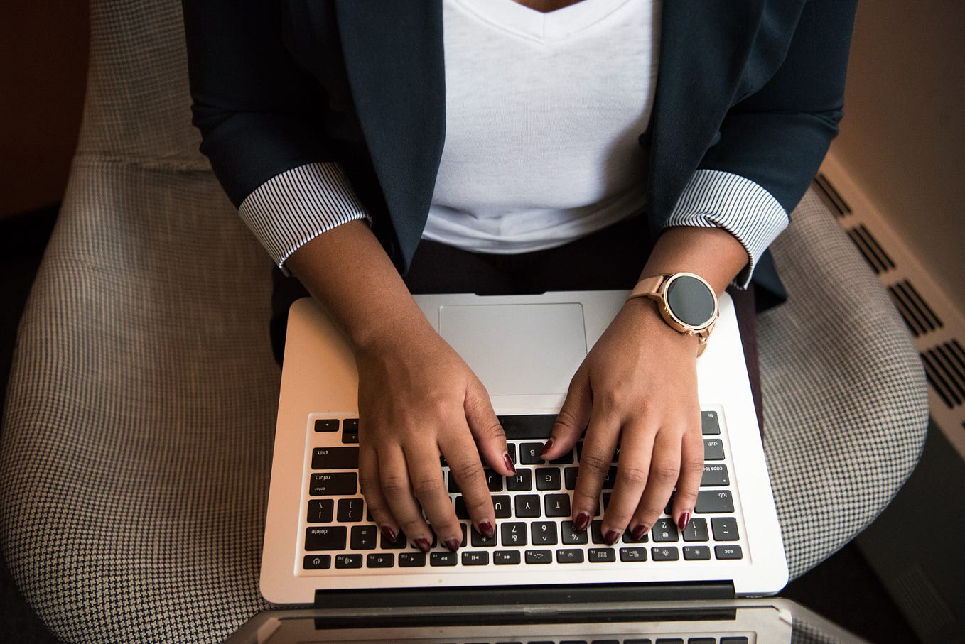 A person in blue coat typing on a laptop