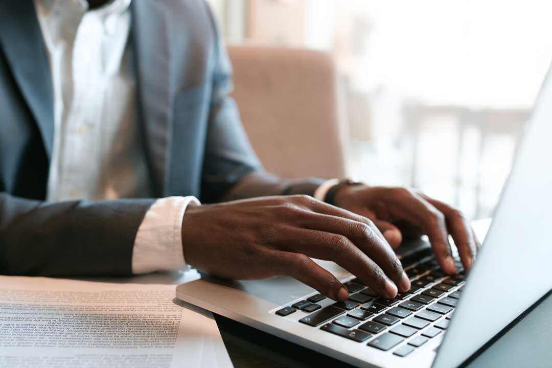 A man in suit typing on a laptop
