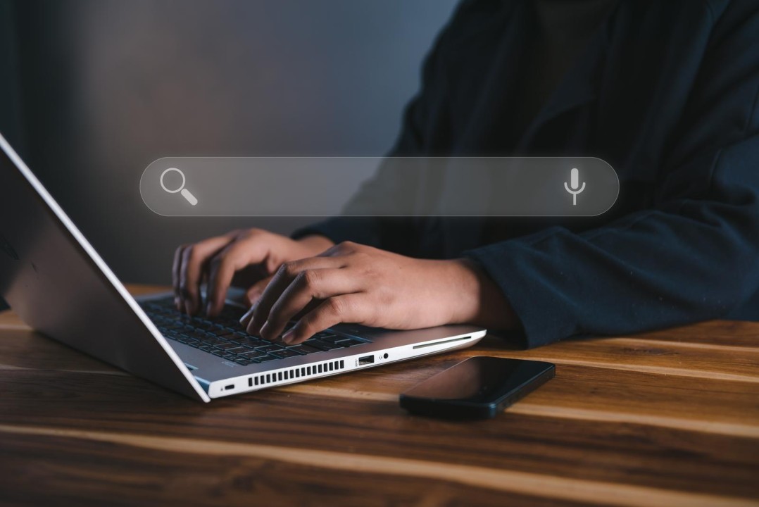A man typing on a laptop with floating search bar