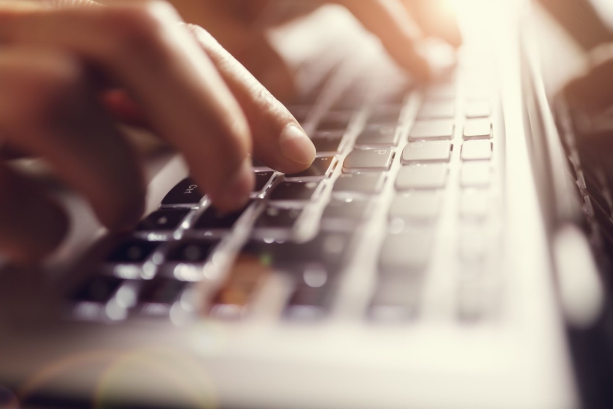 Hands typing on a laptop keyboard