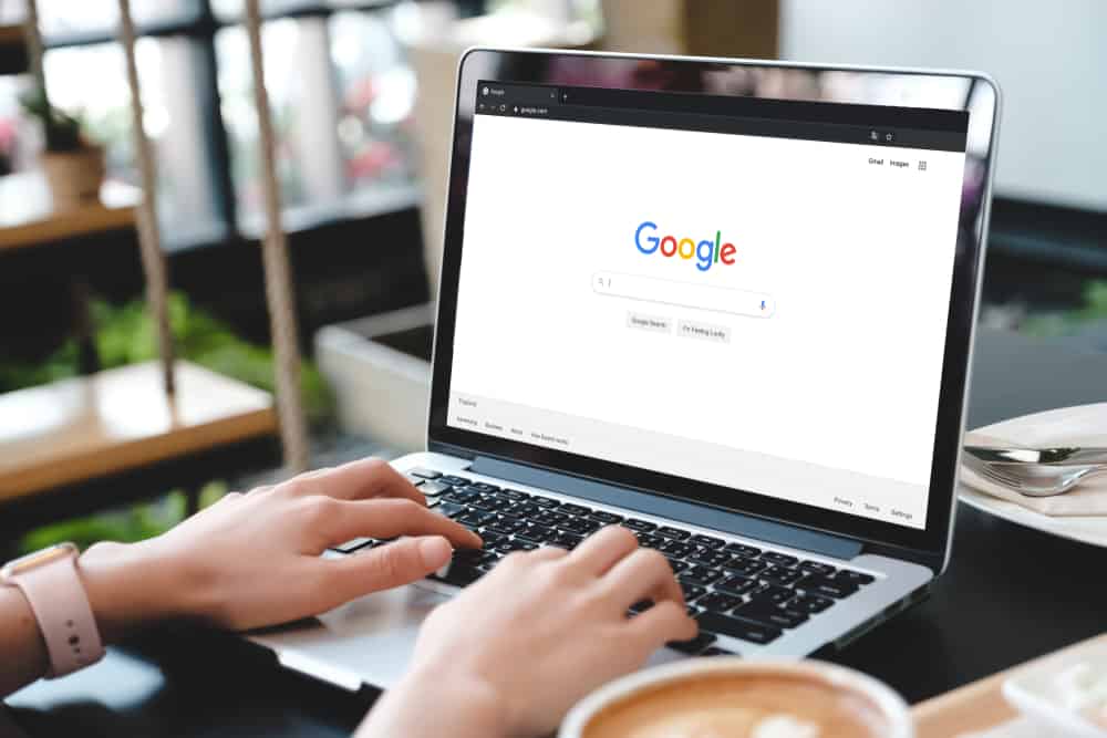 A person typing on a laptop in a Google search engine