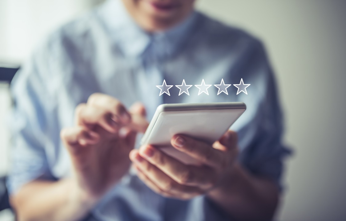 A person holding a phone with five stars